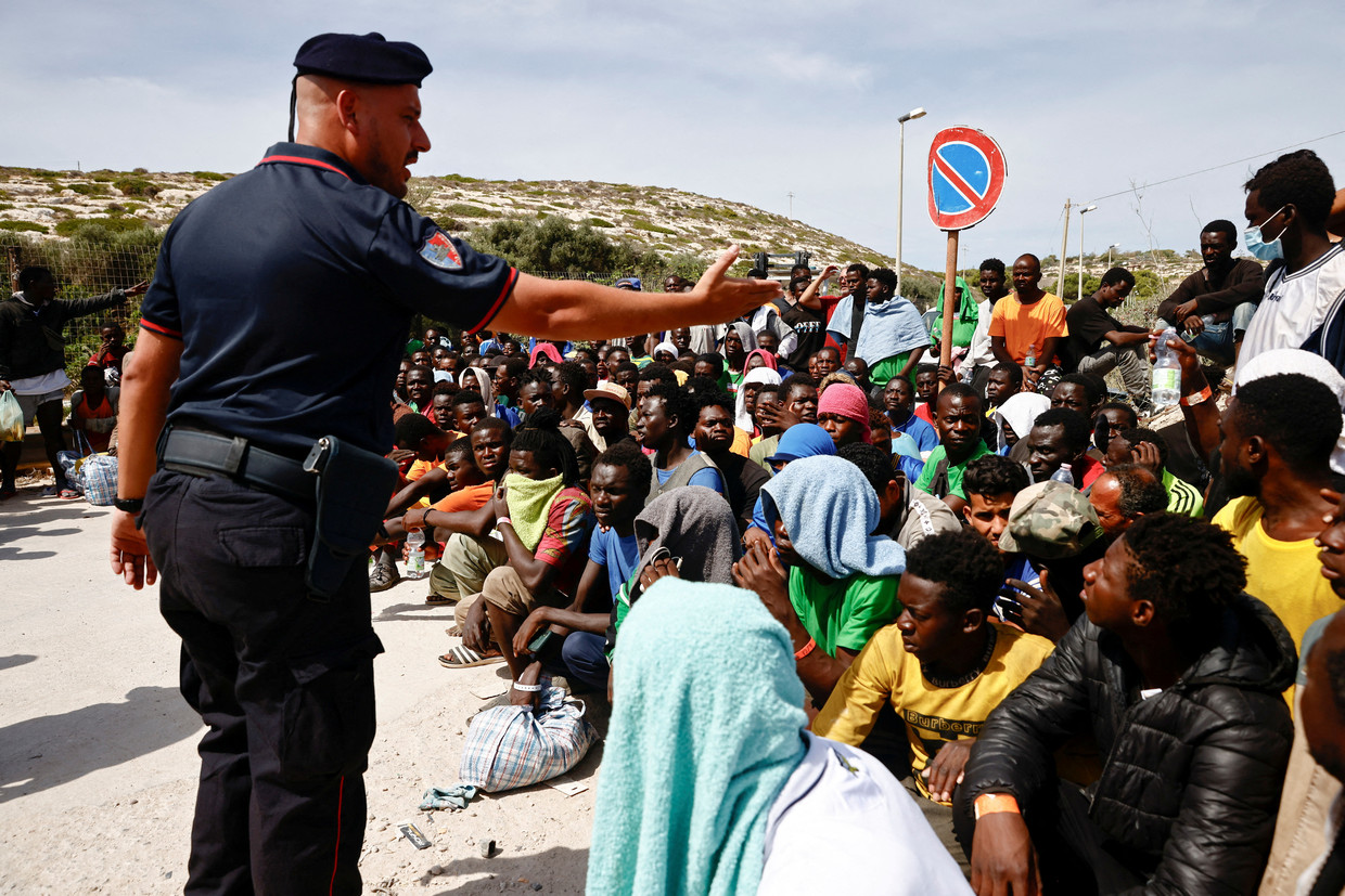 Un agente italiano tra un gruppo di migranti sbarcati sull'isola di Lampedusa.  Foto Reuters/Yara Nardi