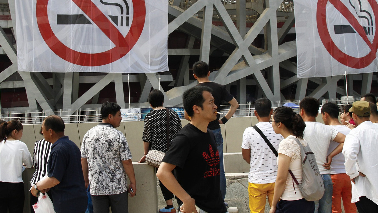 Een man rookt een sigaret in Peking, voor vlaggen ter gelegenheid van Wereld Anti-Tabaksdag op maandag 31 mei. Beeld anp