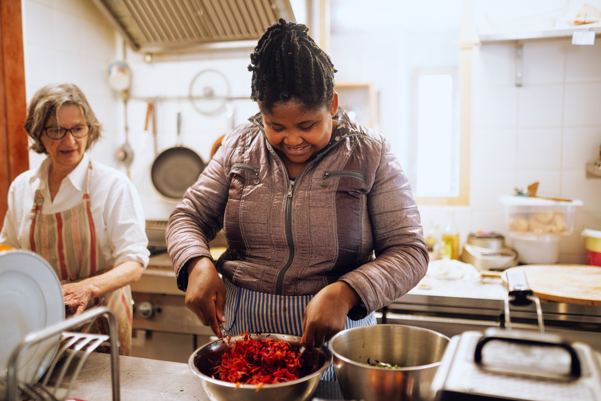 Victoria dalla Nigeria prepara la cena con la volontaria Katie.  Immagine per De Volkskrant di Lina Selk