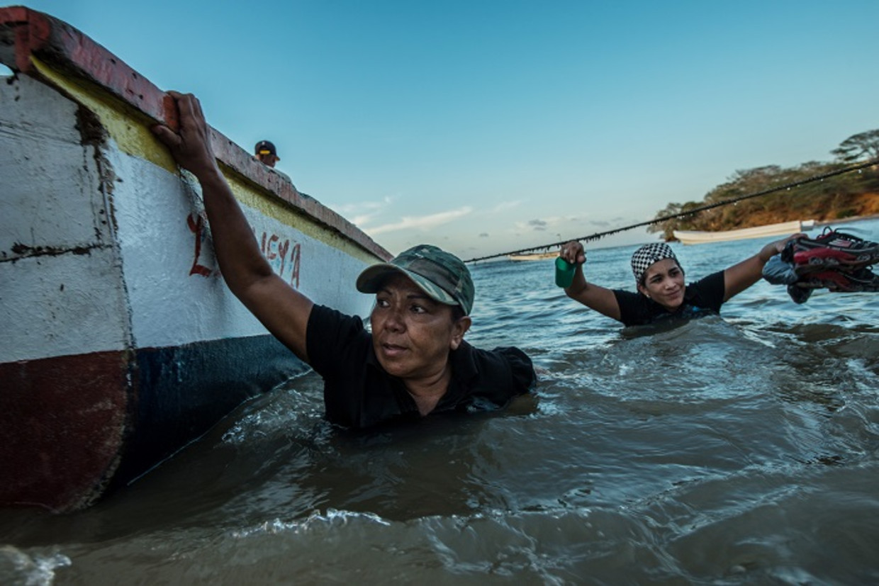 Venezolaanse migranten gaan aan boord van een smokkellaarsboot, die ze naar Curaçao moet gaan brengen. Beeld Foto Meridith Kohut for The New York Times