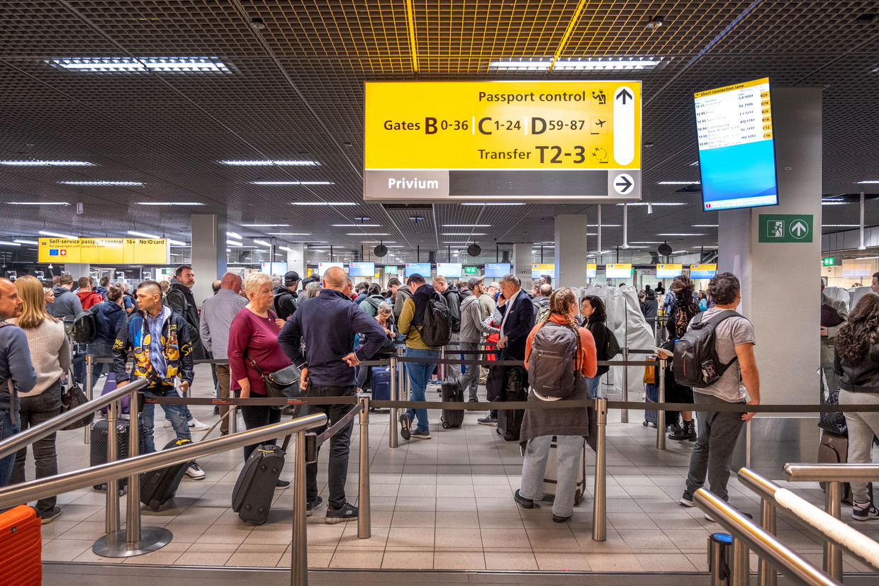 Passagiers wachten voor de paspoortcontrole op Schiphol.  Beeld Raymond Rutting / de Volkskrant